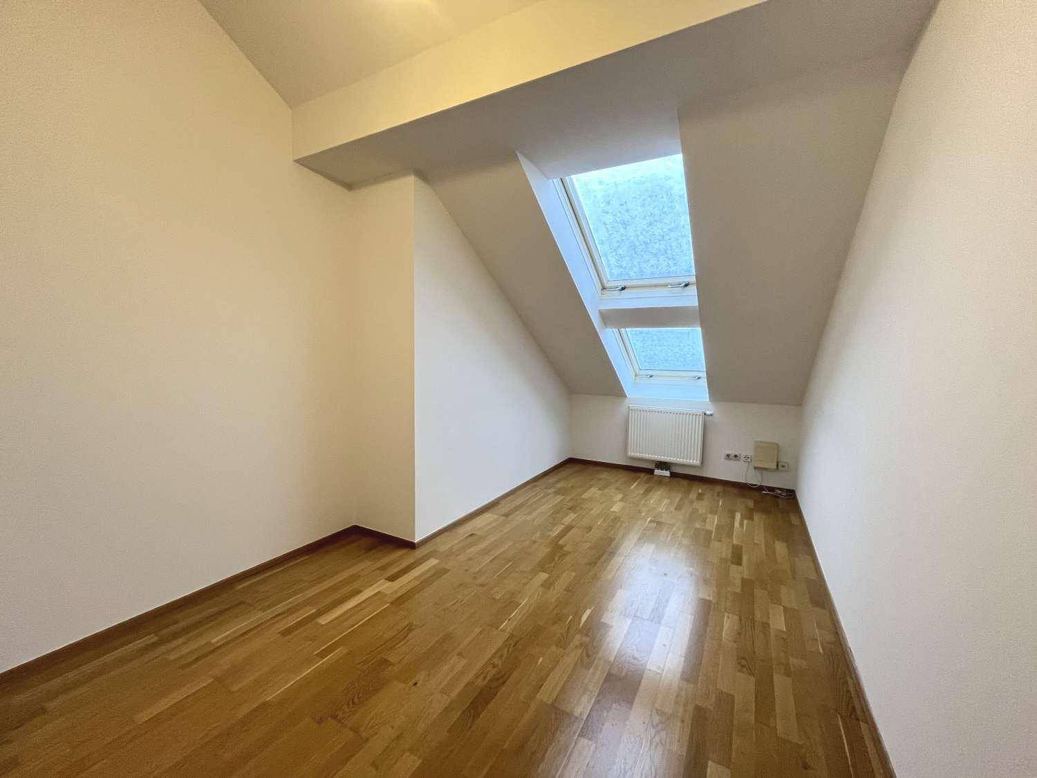 Helles Zimmer mit Holzboden und zwei Dachfenstern, ideal als Schlaf- oder Arbeitszimmer.