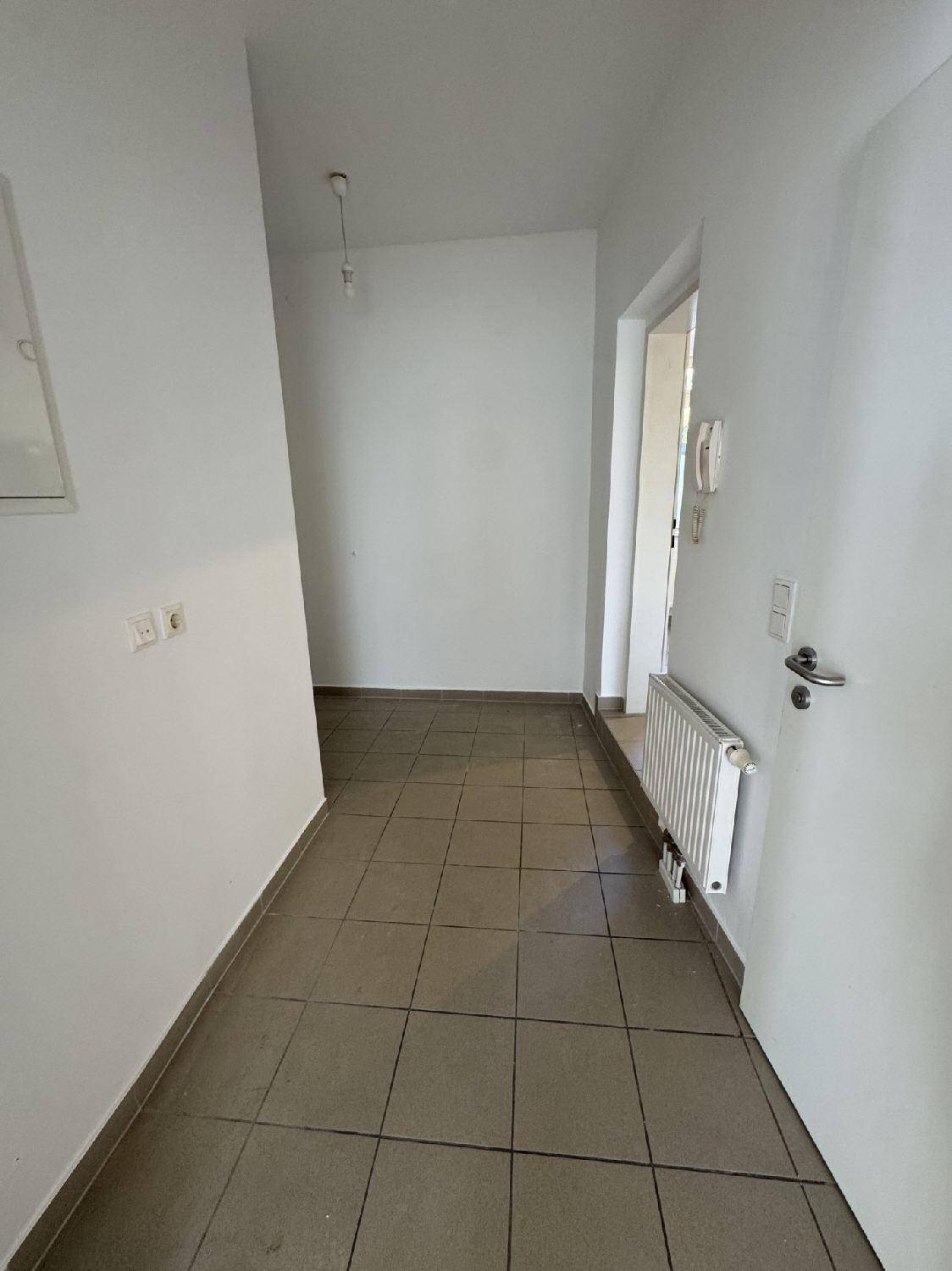 Langer, heller Flur mit Fliesenboden und weiß gestrichenen Wänden, der zu den Zimmern führt.