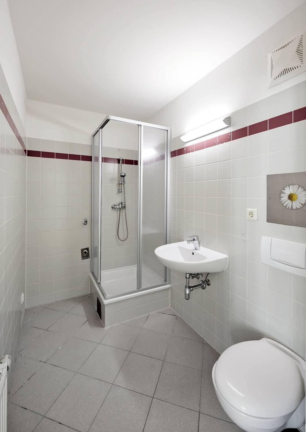 Kleines Badezimmer mit Duschkabine, Waschbecken und WC, ausgestattet mit hellgrauen Fliesen.