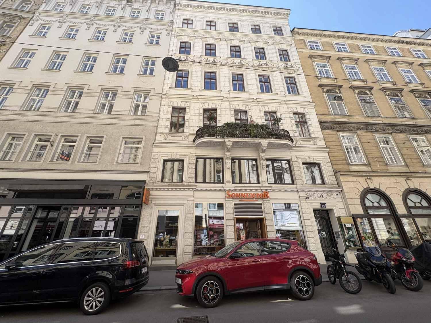 Historisches Mehrfamilienhaus in einer belebten Stadtstraße mit reich verzierter Fassade und Balkonen.