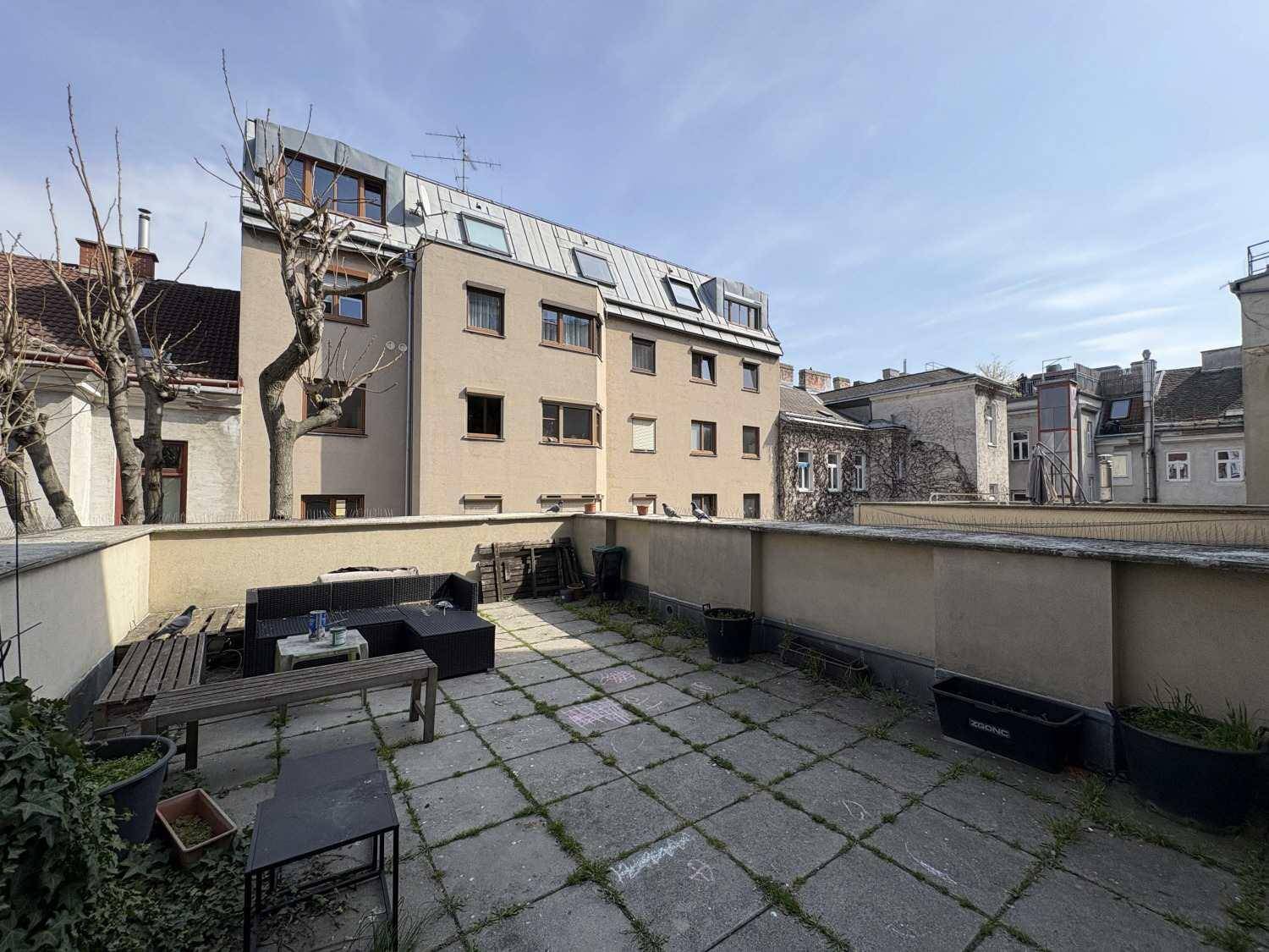 Geräumige Außenterrasse mit Sitzgelegenheiten und Blick auf die umliegenden Gebäude.