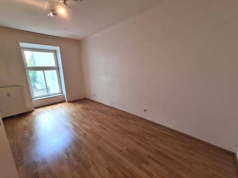 Gemütliches Zimmer mit Parkettboden und einem Fenster, das für ausreichend Tageslicht sorgt.