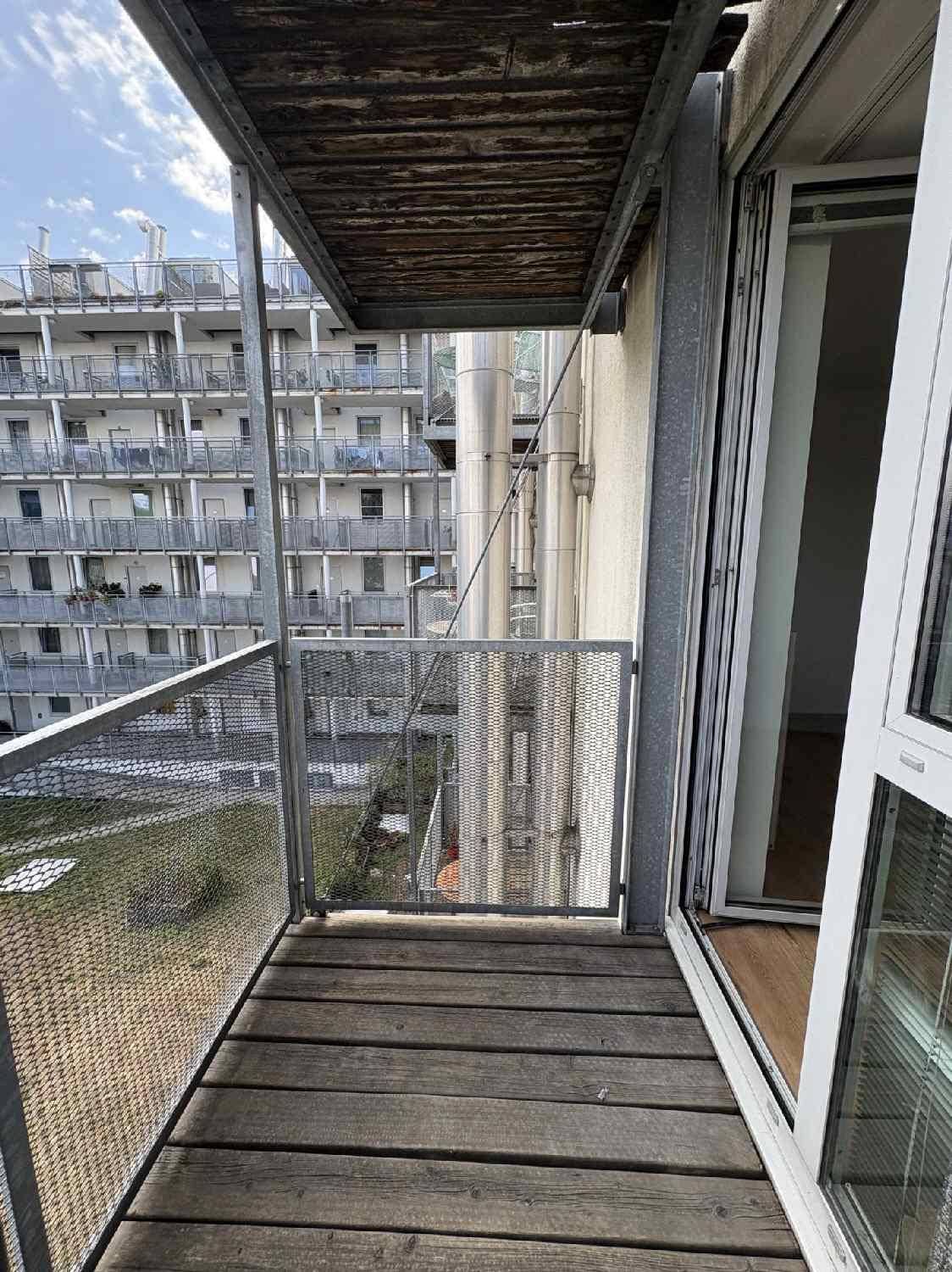 Blick vom Balkon auf die umliegenden Gebäude und die darunterliegende Struktur mit Holzboden.
