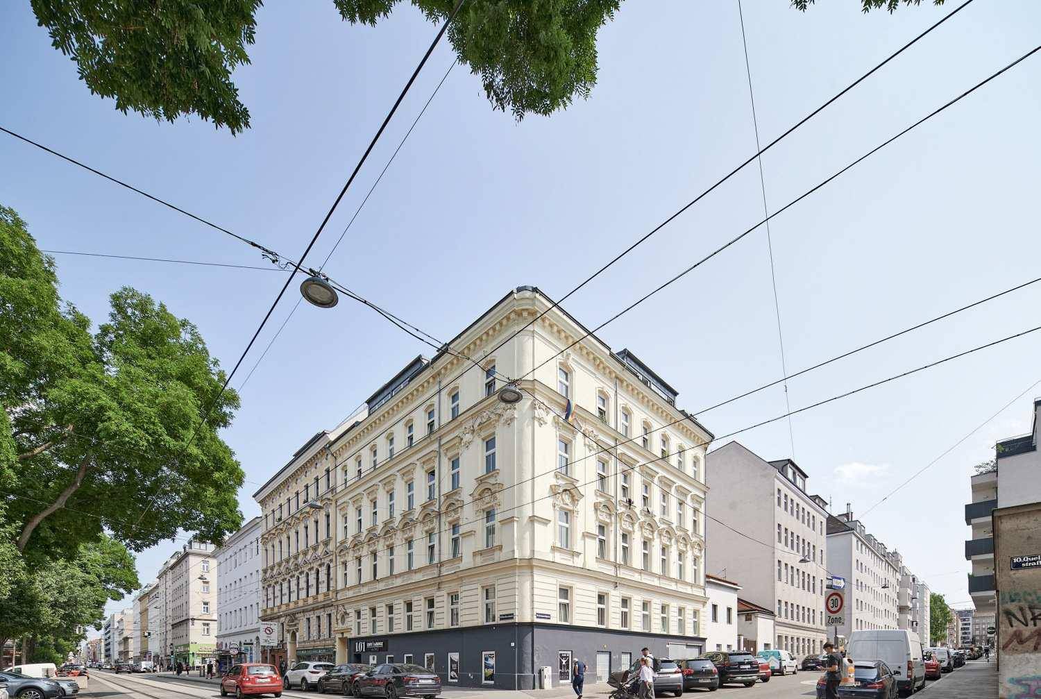 Historisches Eckgebäude mit klassischer Architektur und vielen Fenstern an einer belebten Straße.