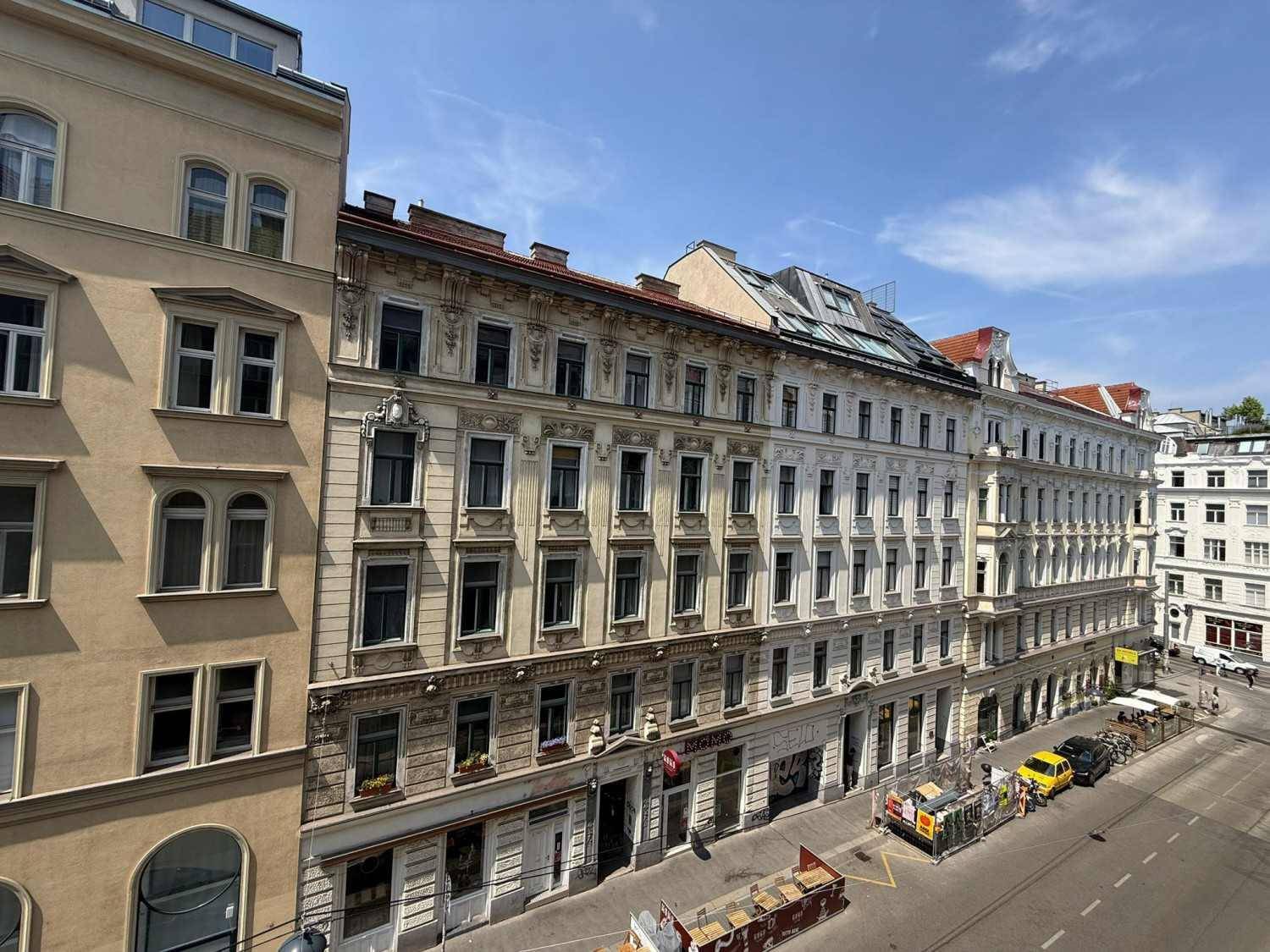 Historische Gebäude entlang einer belebten Straße mit vielen Fenstern und architektonischen Details.