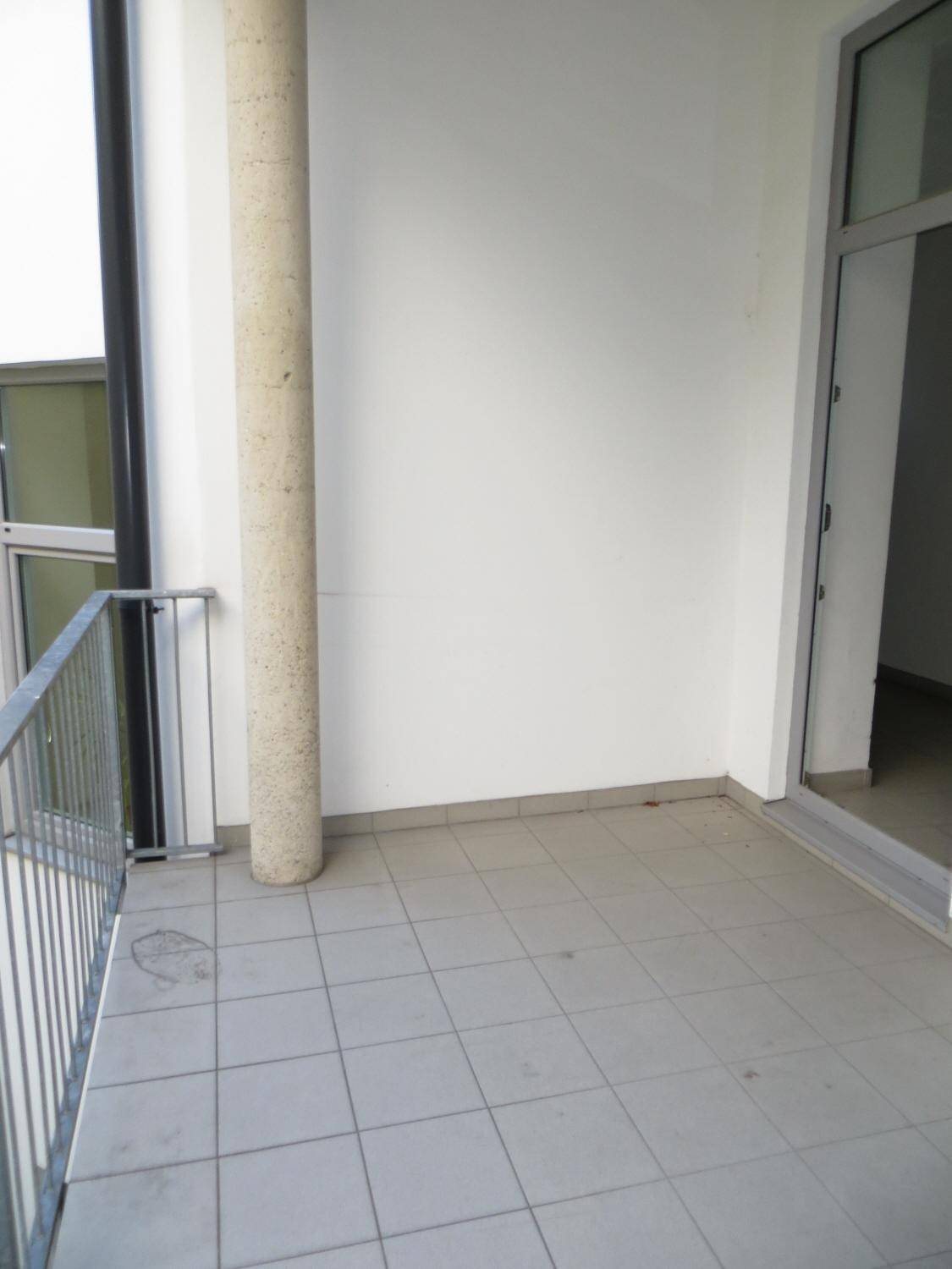 Kleiner gefliester Balkon mit einer Säule und direktem Zugang zum Innenraum der Wohnung.