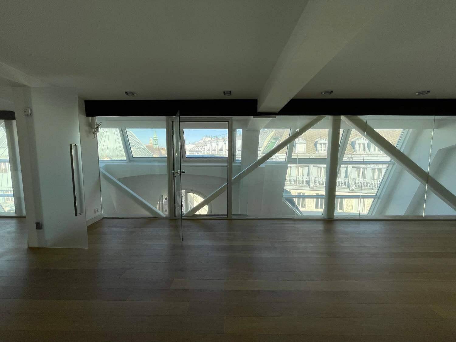 Geräumiger Raum mit großen Fenstern, Holzboden und Blick auf die Stadt, ideal für ein offenes Wohnkonzept.