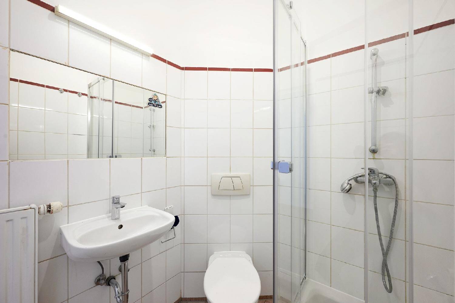 Helles Badezimmer mit Duschkabine, Waschbecken und WC, sauber gefliest und praktisch eingerichtet.