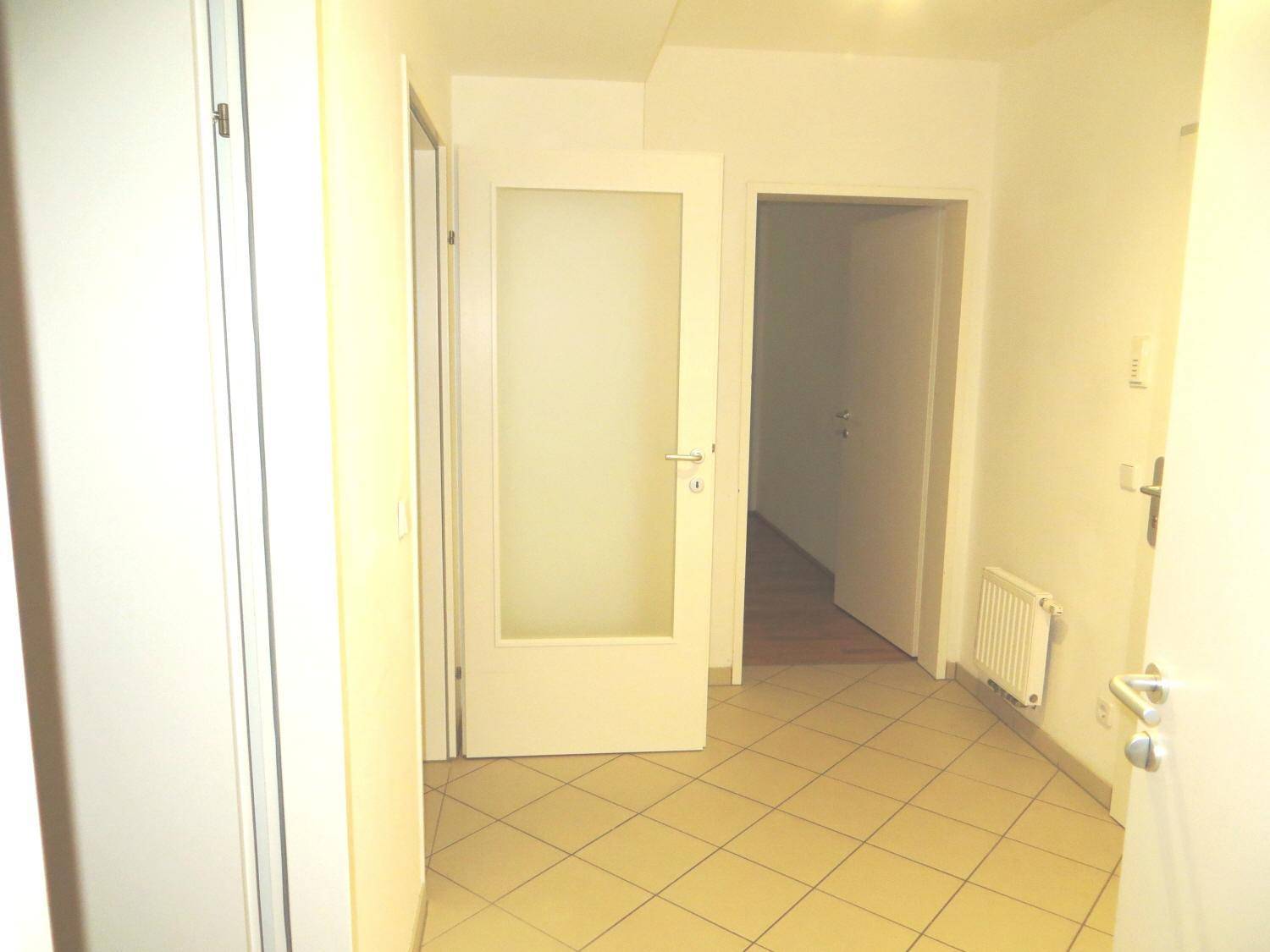 Heller Flur mit Fliesenboden und mehreren Türen, darunter eine mit Milchglas.