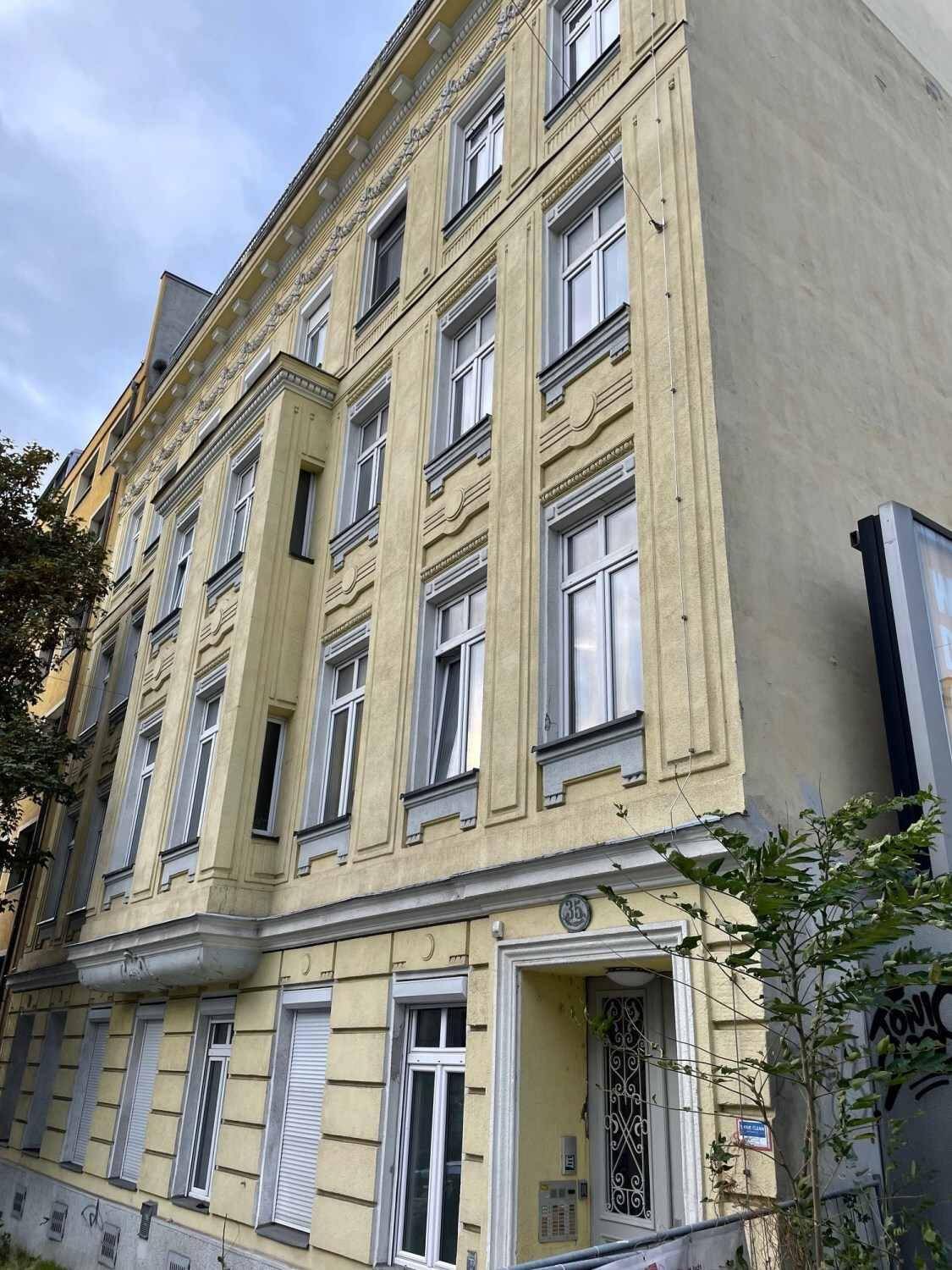 Detailansicht der historischen Gebäudefassade mit Stuckverzierungen und Fensterläden.