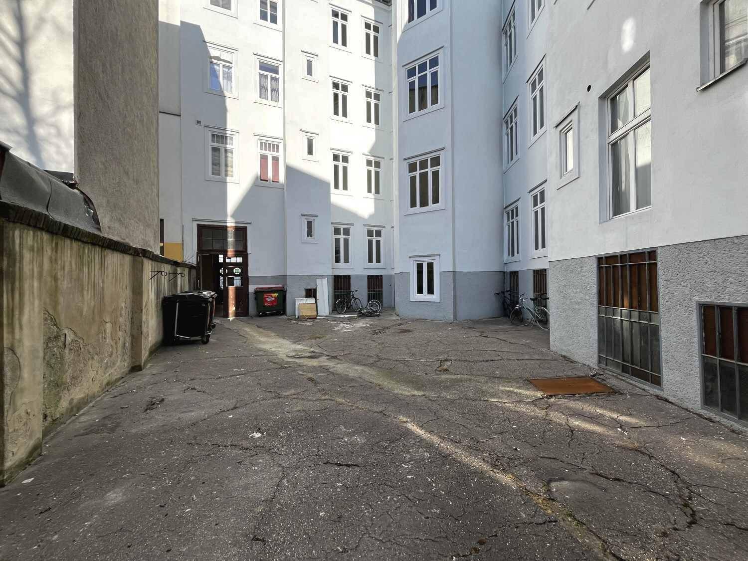 Innenhof eines Wohngebäudes mit hellen Fassaden und abgestellten Fahrrädern.