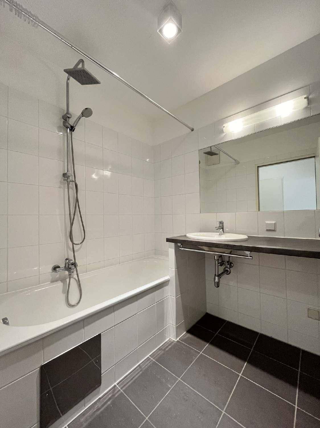 Funktionales Badezimmer mit Badewanne, Duschvorrichtung und modernen Fliesen in Grau und Weiß.