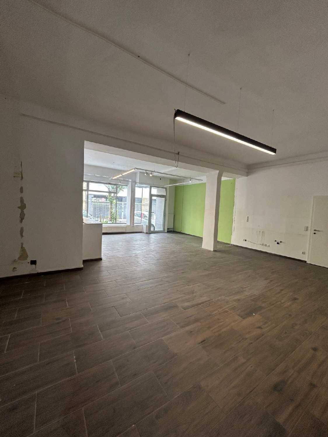 Weitläufiger Gewerberaum mit großen Fenstern zur Straße und einem modernen Beleuchtungssystem.