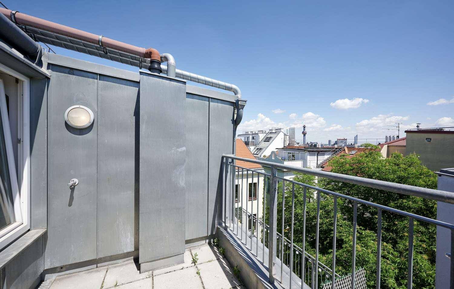 Kleiner Balkon mit Metallgeländer und Blick über die Dächer der Stadt.