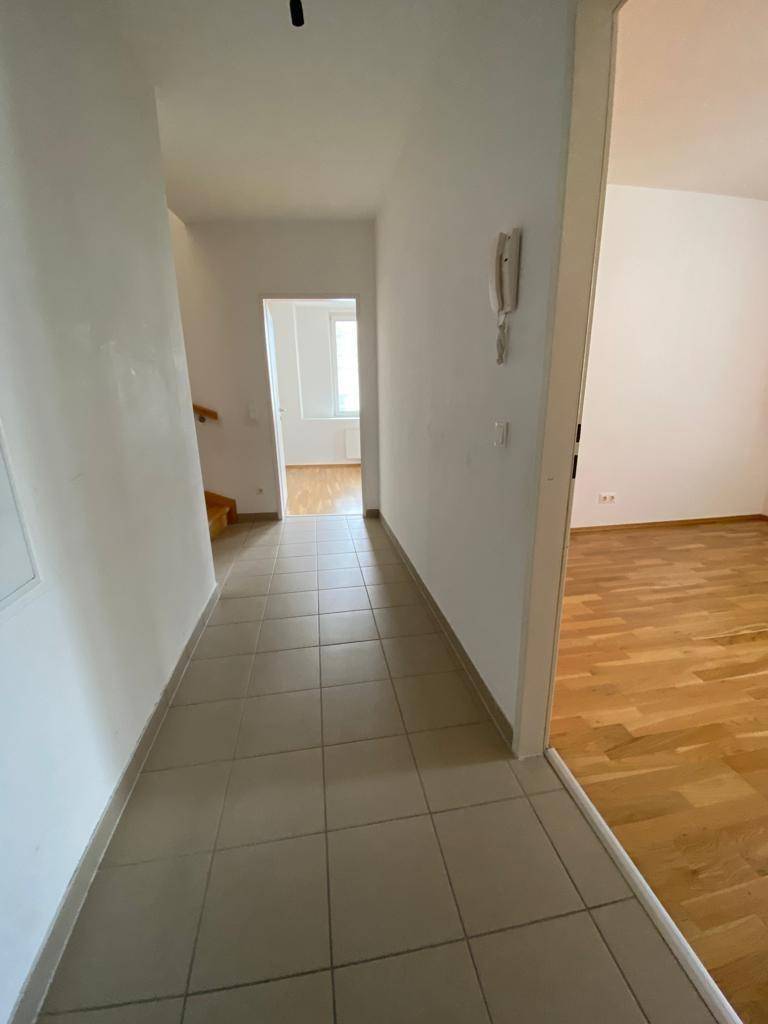 Langer Flur mit Fliesenboden, Gegensprechanlage und Zugang zu verschiedenen Zimmern.
