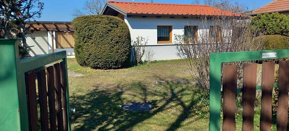 Vorgarten mit grünem Zaun und Blick auf das Haus mit rotem Ziegeldach.
