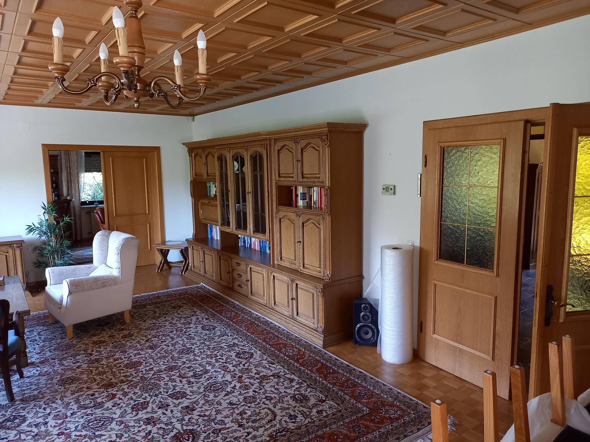 Traditionelles Wohnzimmer mit Holzkassettendecke, Parkettboden und antiken Holzmöbeln.