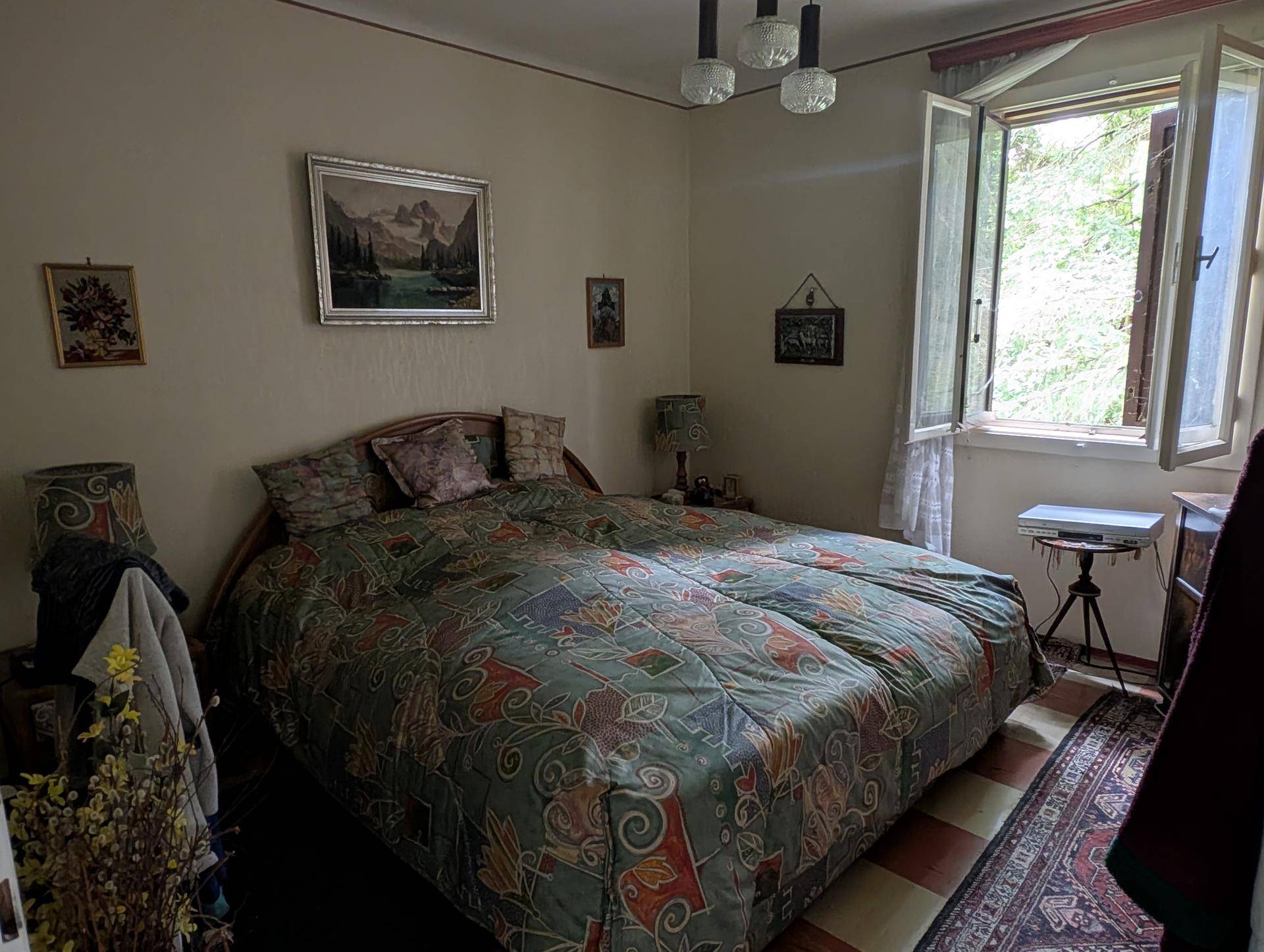 Gemütliches Schlafzimmer mit Doppelbett, klassischer Einrichtung und einem Fenster mit Blick ins Grüne.