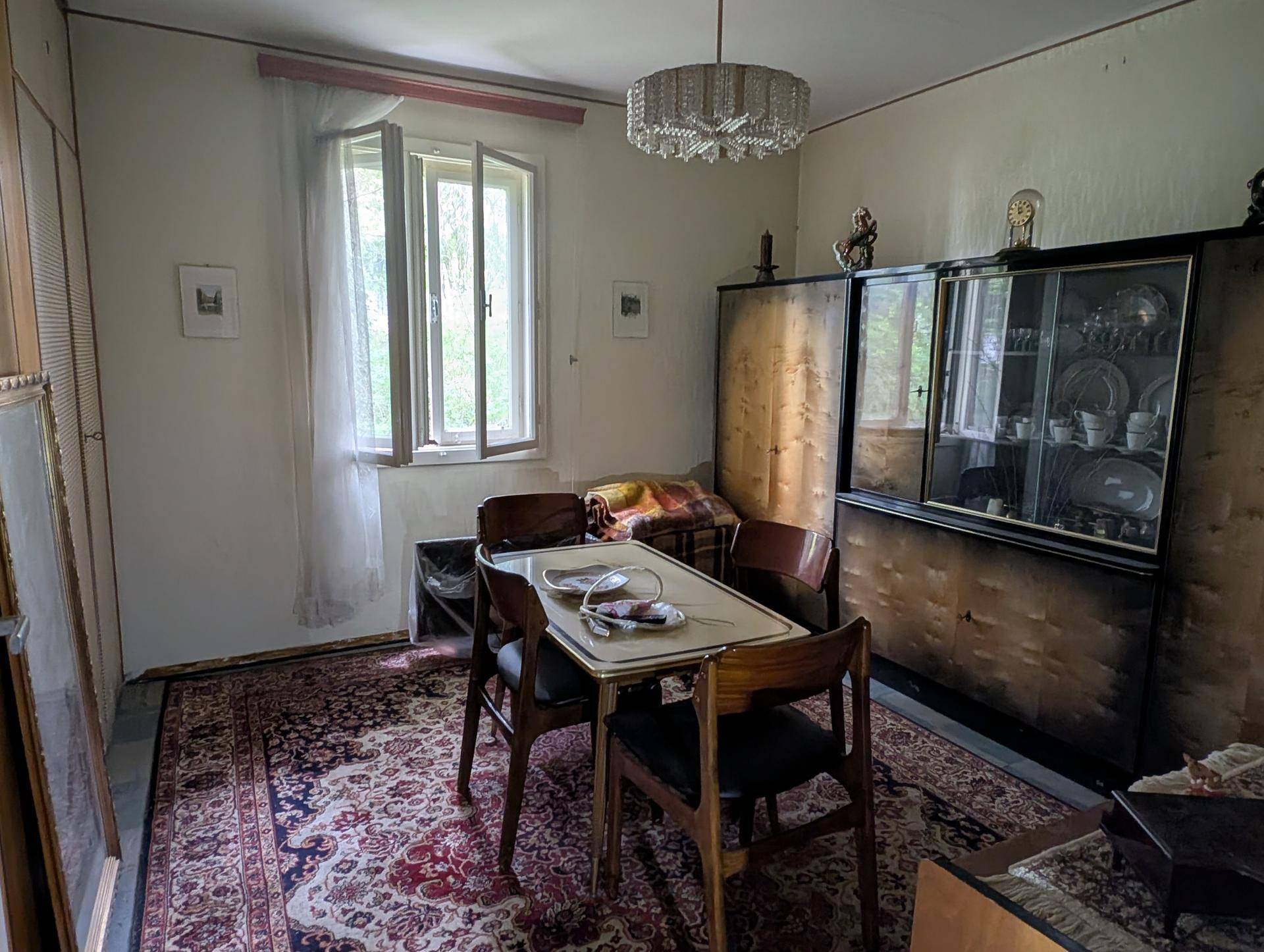 Kleineres Esszimmer mit einem Holztisch, passenden Stühlen und einem Vitrinenschrank im klassischen Stil.