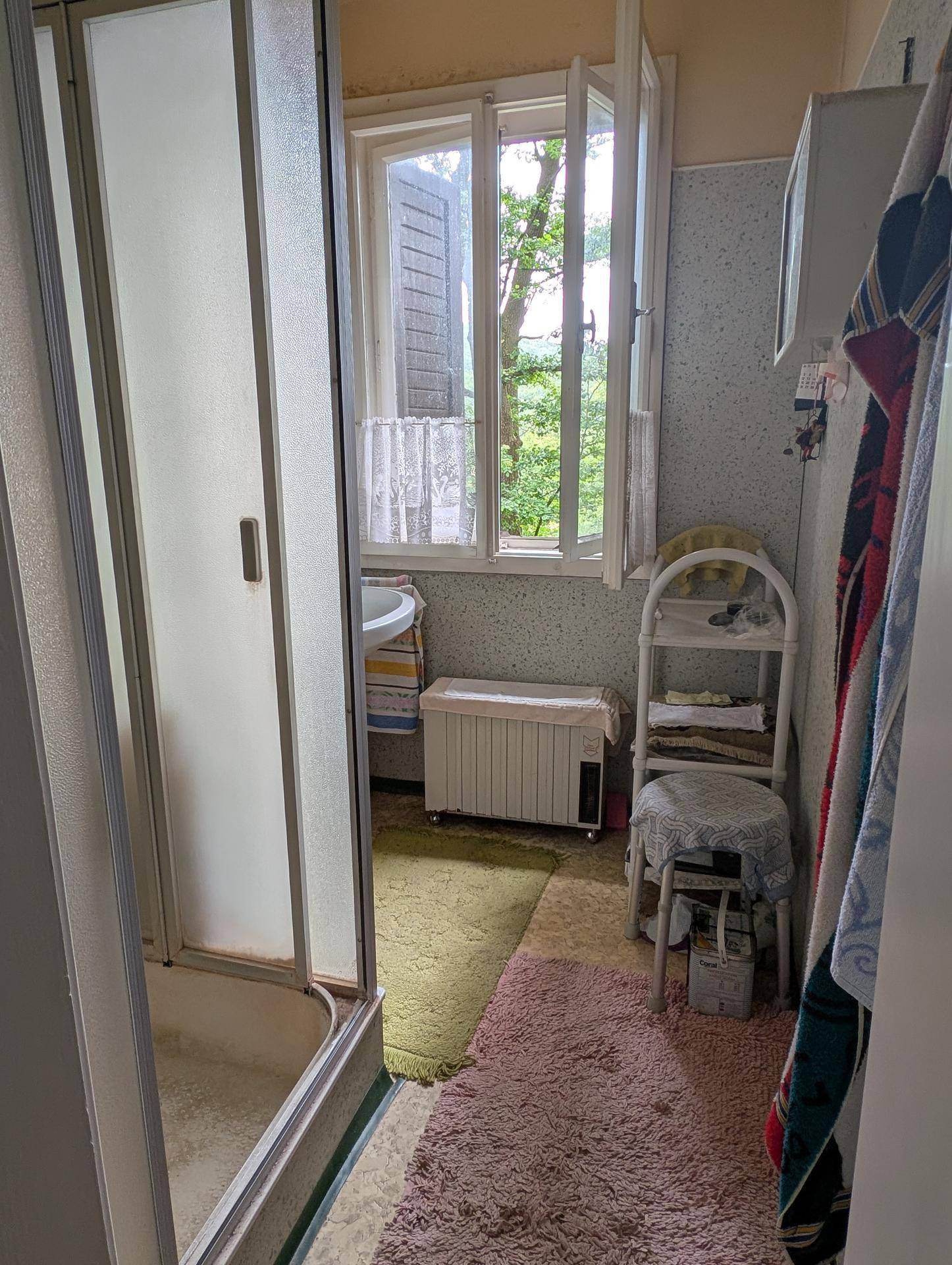 Funktionales Badezimmer mit Duschkabine, Waschbecken und einem Fenster für Tageslicht und Belüftung.