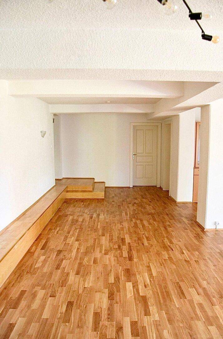 Heller Raum mit Holzboden und einer integrierten Holzbank, ideal für individuelle Gestaltung.