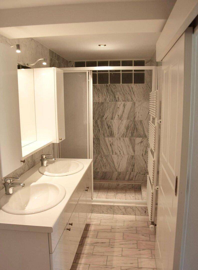 Elegantes Badezimmer mit Doppelwaschbecken, Spiegelschrank und geräumiger Duschkabine.
