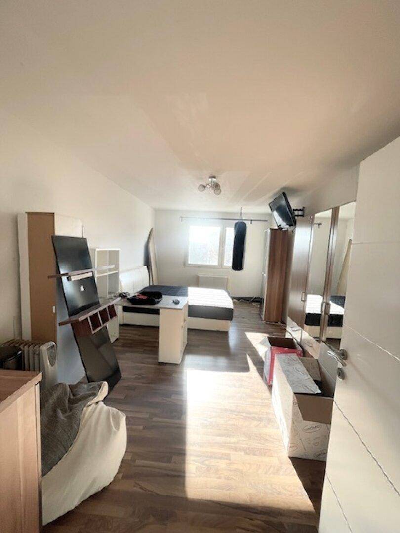 Schlafzimmer mit Laminatboden, Bett und Schränken, durchflutet von Sonnenlicht.