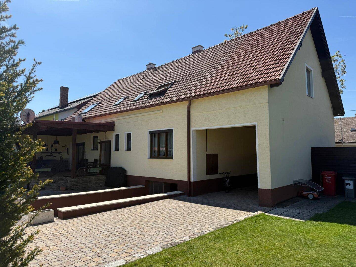 Seitenansicht des Hauses mit gepflasterter Einfahrt, Garage und angrenzendem Gartenbereich.