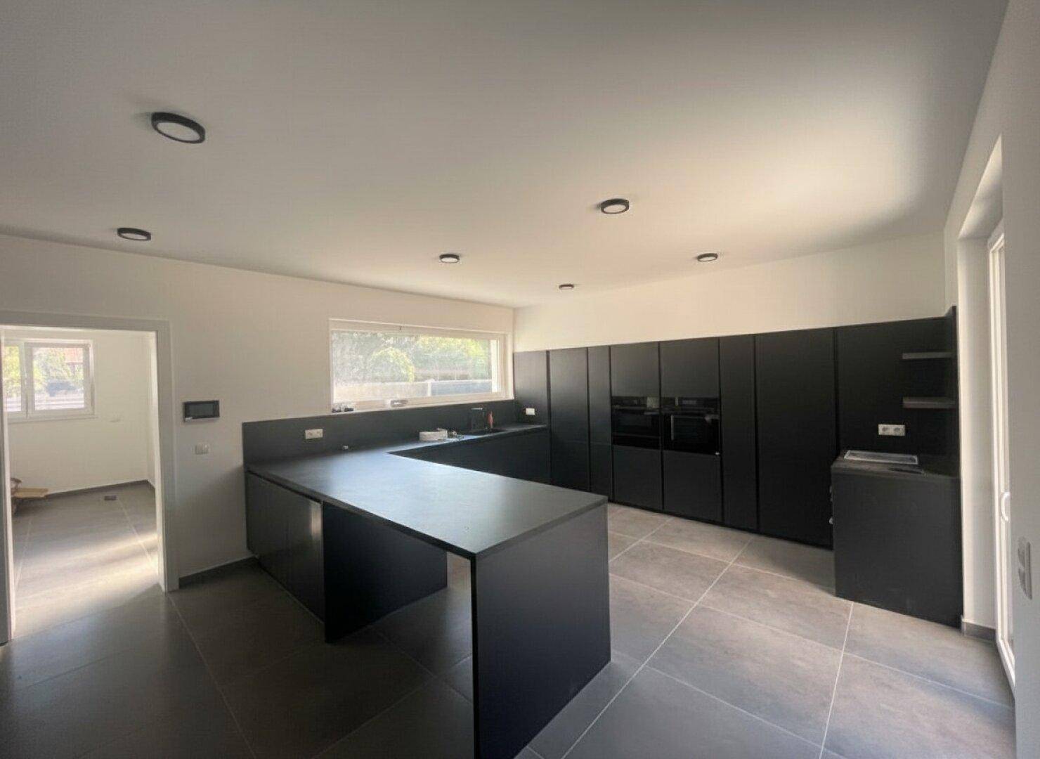 Offene, moderne Küche in Schwarz mit Kücheninsel und viel Stauraum, ideal für geselliges Kochen.