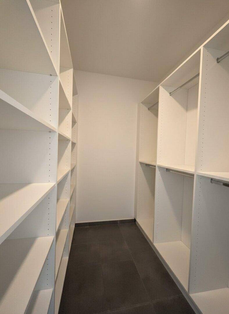 Praktischer begehbarer Kleiderschrank mit vielen Regalen und Stangen für optimale Organisation.
