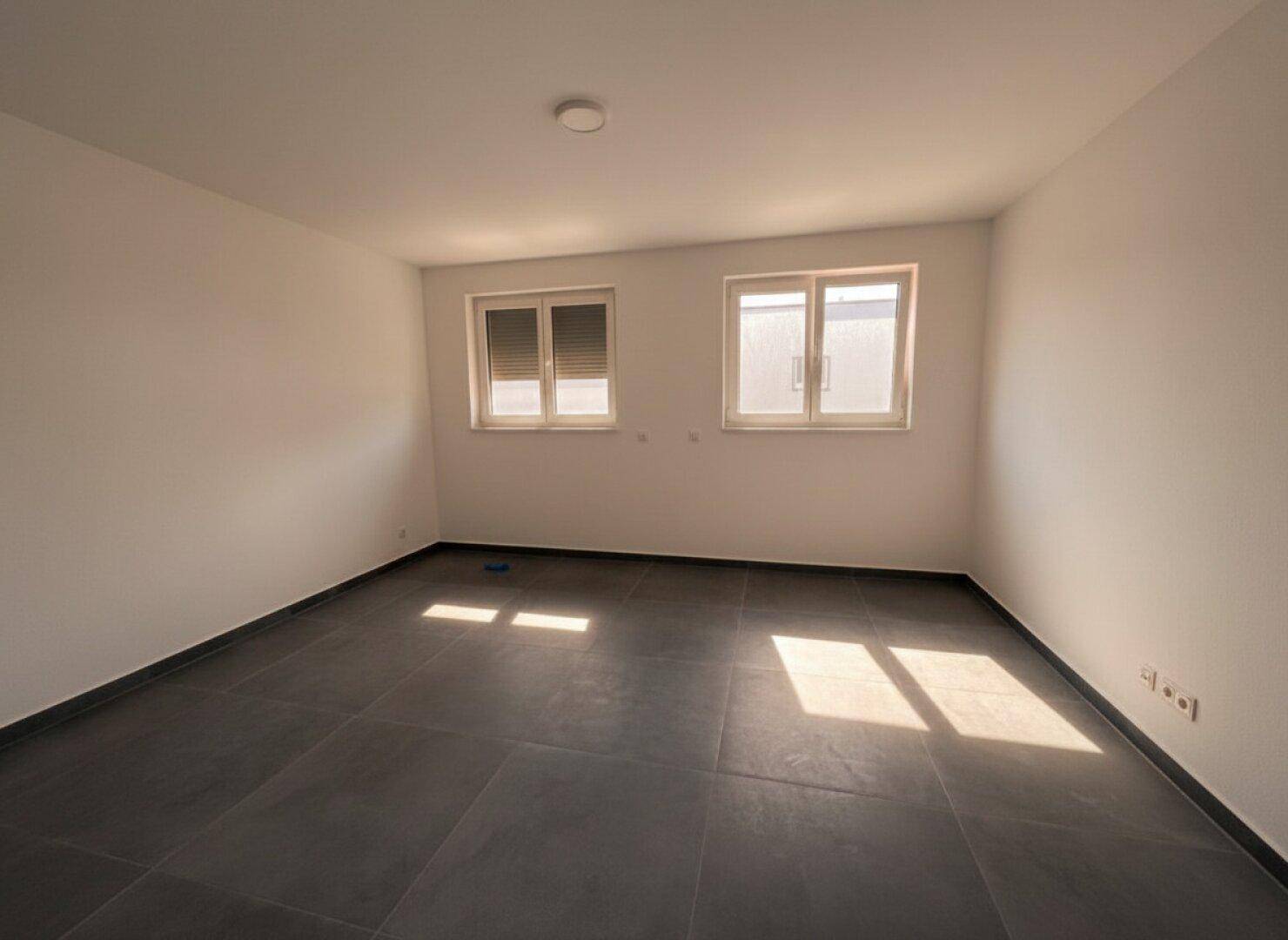 Helles Schlafzimmer mit zwei Fenstern und Fliesenboden, ideal für ein ruhiges Ambiente.