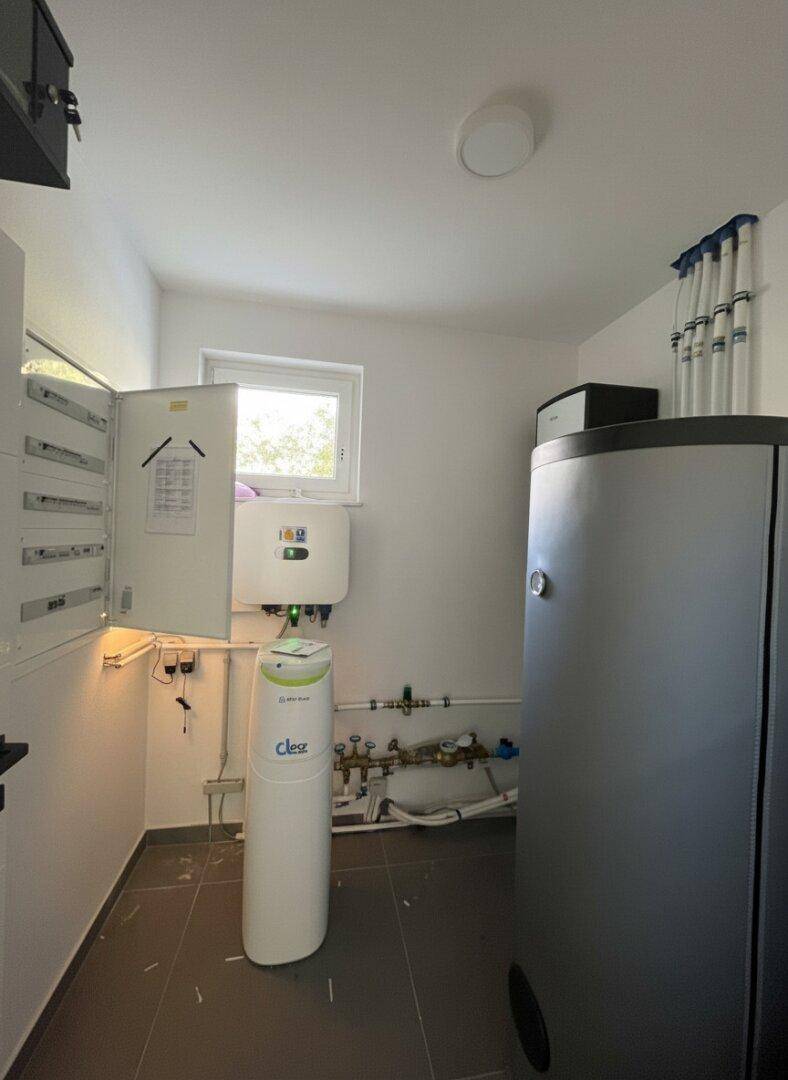 Technikraum mit moderner Heizungsanlage, Warmwasserspeicher und Wasseraufbereitungssystem.