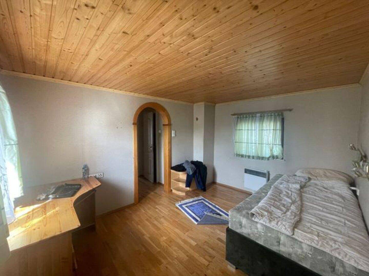 Gemütliches Schlafzimmer mit Holzbalkendecke, Holzboden und einem Einzelbett.