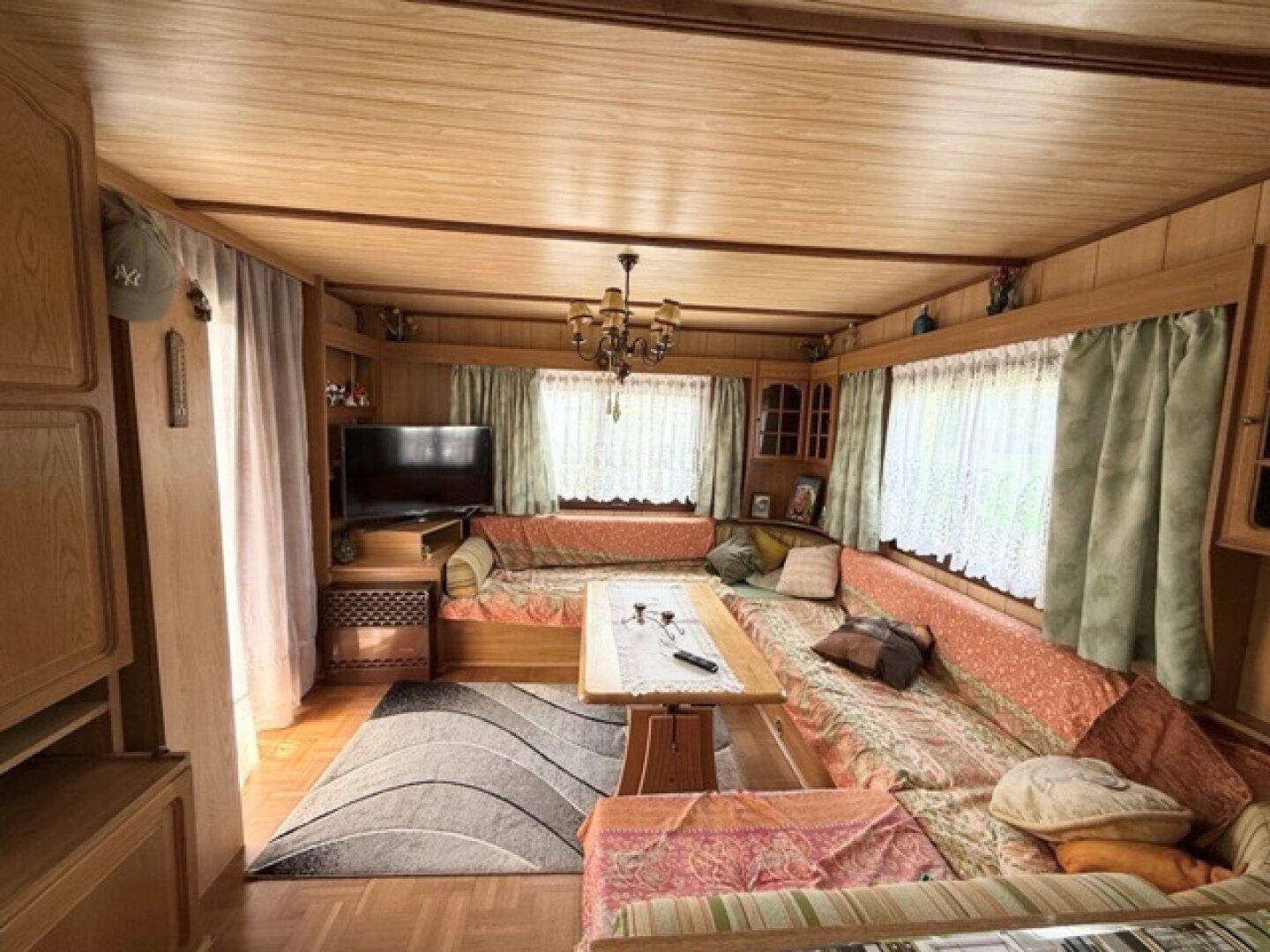 Gemütliches Wohnzimmer mit Holzvertäfelung, Ecksofa und traditioneller Einrichtung.
