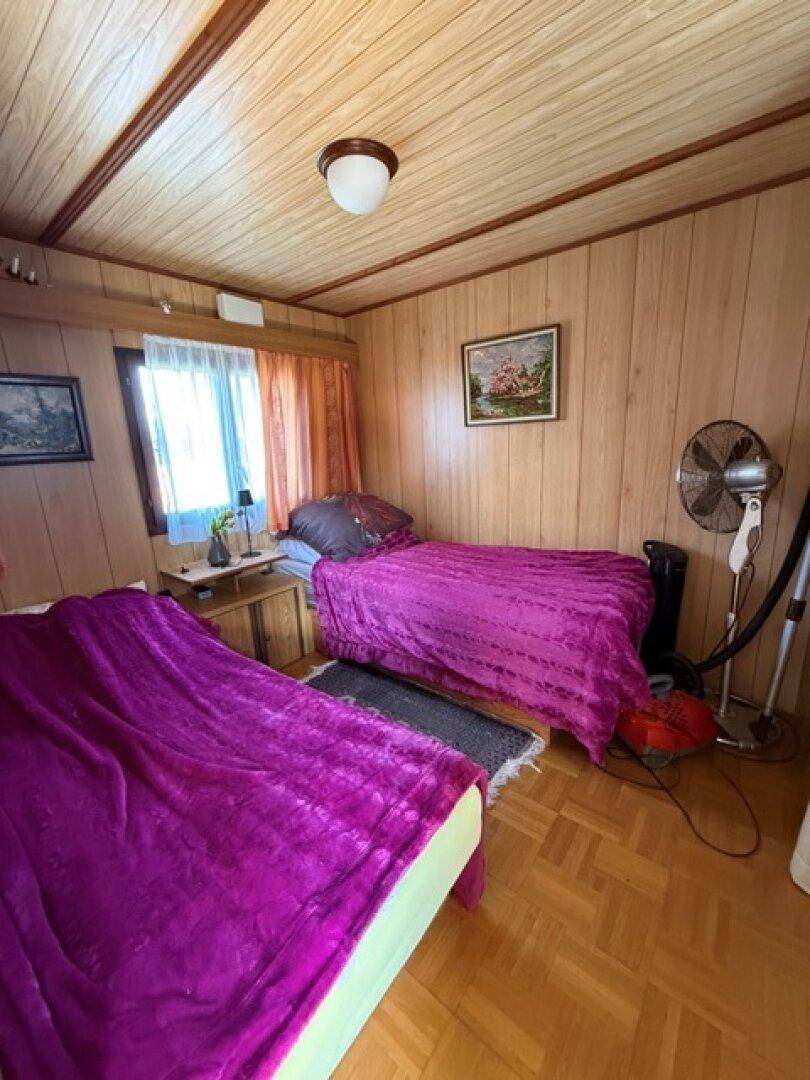 Schlafzimmer mit Holzvertäfelung, zwei Einzelbetten und einem Fenster.
