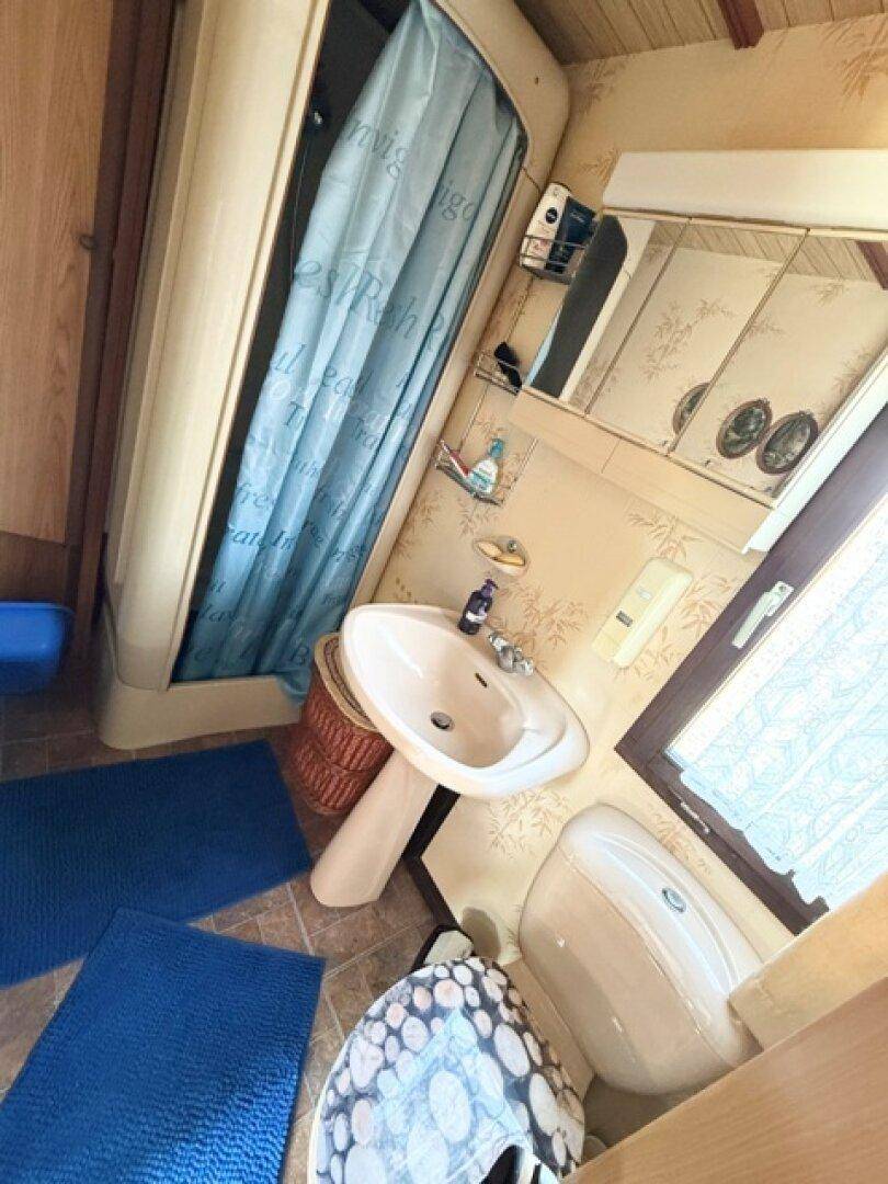 Kleines Badezimmer mit Dusche, Waschbecken und WC, ausgestattet mit einem Fenster.