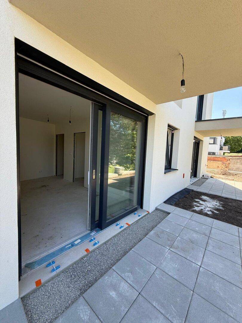 Überdachte Terrasse mit Schiebetür, die Zugang zu einem hellen Innenraum bietet.