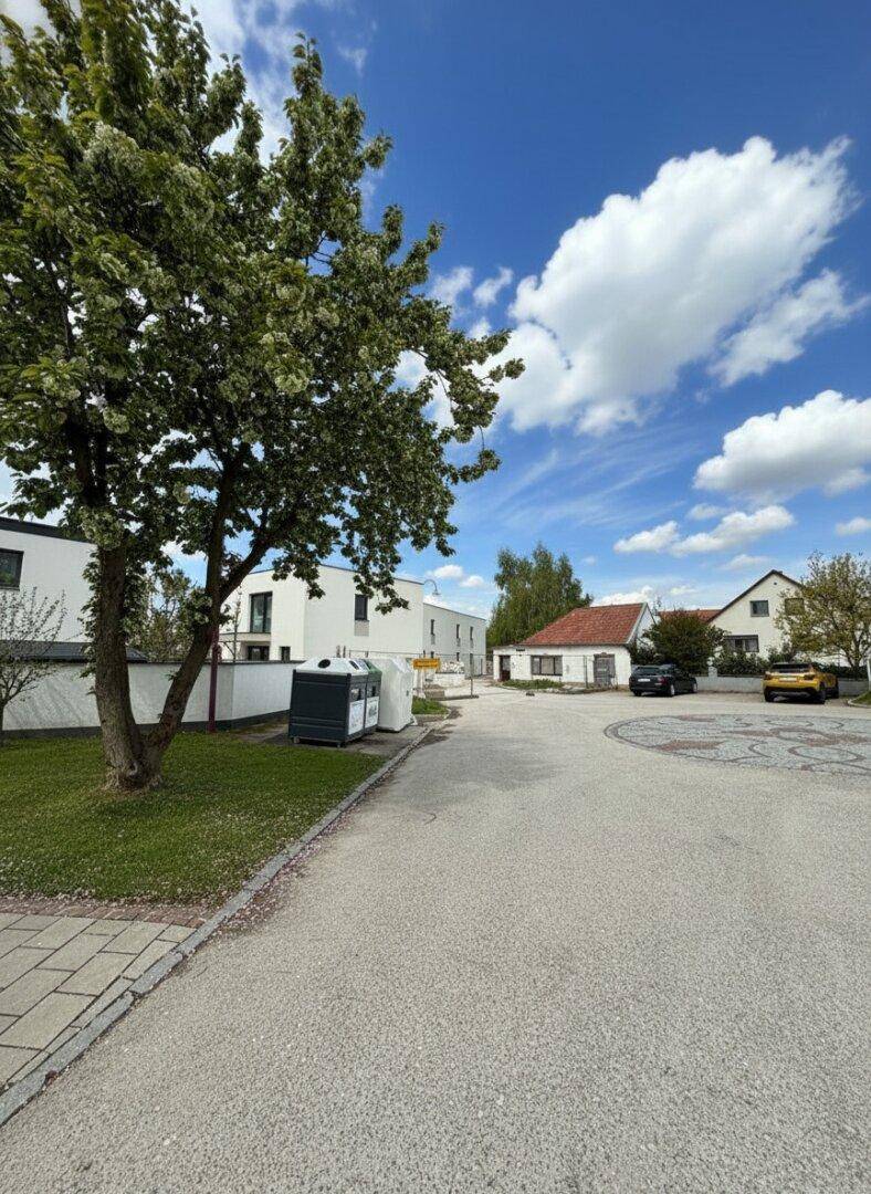 Weitläufige Ansicht der Wohngegend mit modernen Gebäuden, Bäumen und einem sonnigen Himmel.