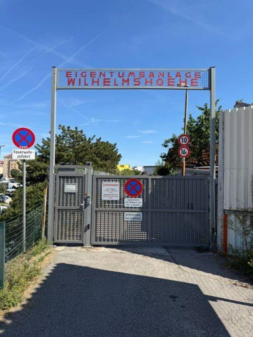 Eingangstor zur Eigentumsanlage Wilhelmshöhe mit Hinweisschildern und Absperrungen.