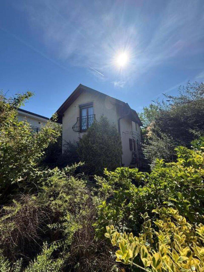 Das Haus ist von einem üppigen Garten umgeben, mit viel Grün und einem sonnigen Himmel.