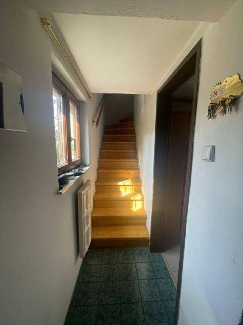 Heller Flur mit Holztreppe, die in die obere Etage führt, und einem Fenster.