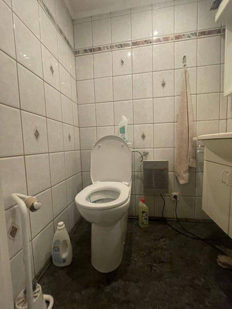 Einfaches WC mit Fliesen an Wänden und Boden, funktional und sauber.