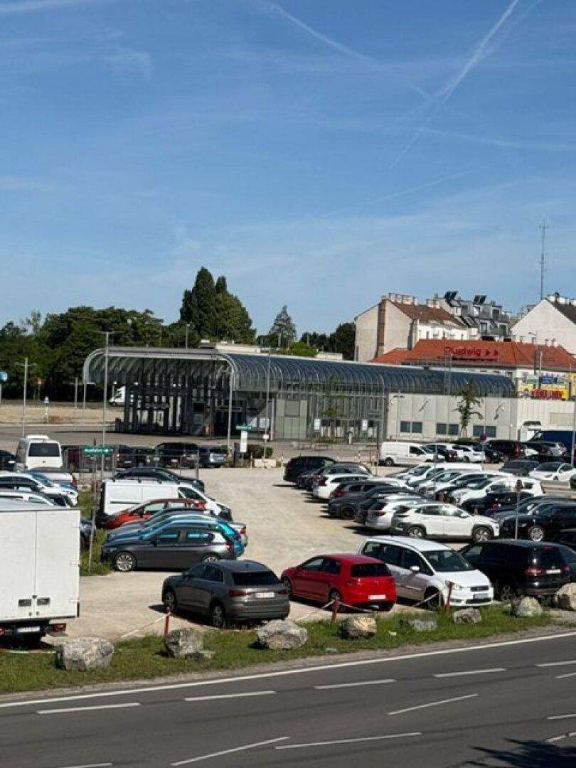 Großer Parkplatz mit vielen Autos und modernen Gebäuden in der näheren Umgebung des Anwesens.