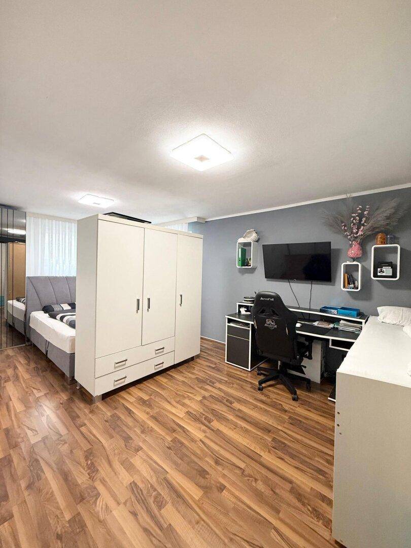 Geräumiges Schlafzimmer mit Holzboden, großem Kleiderschrank und Schreibtischbereich.