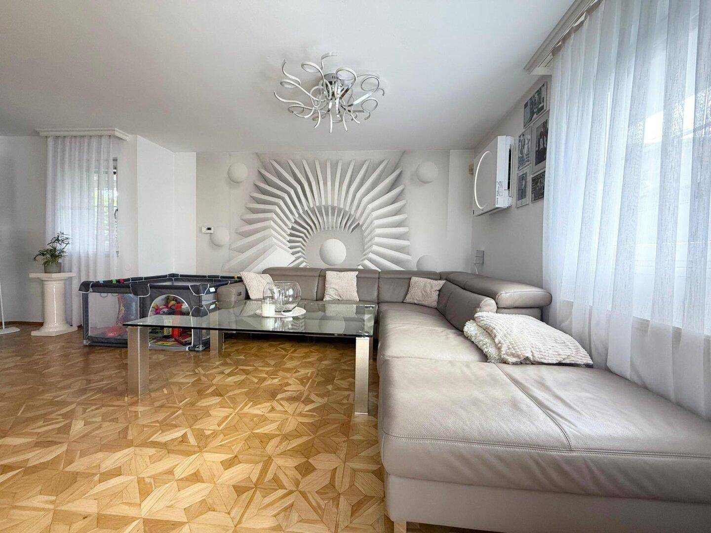 Helles Wohnzimmer mit großem Ecksofa, Parkettboden und dekorativer Wandgestaltung.