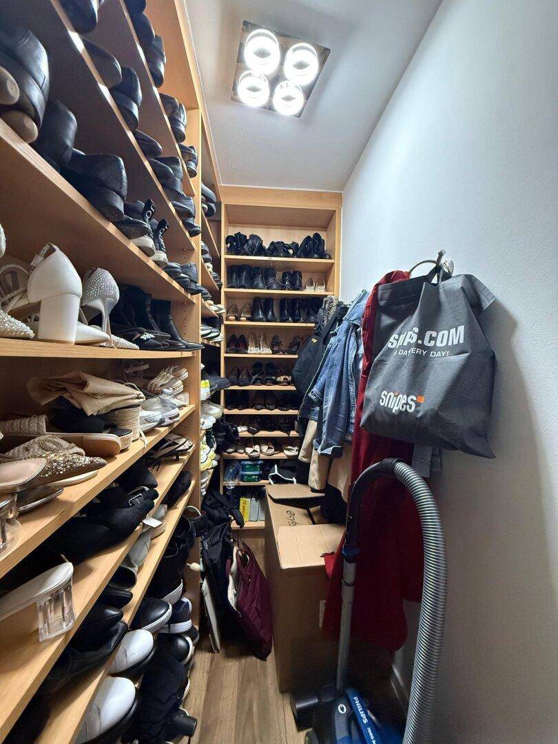 Gut organisierter begehbarer Kleiderschrank mit vielen Regalen für Schuhe und Kleidung.