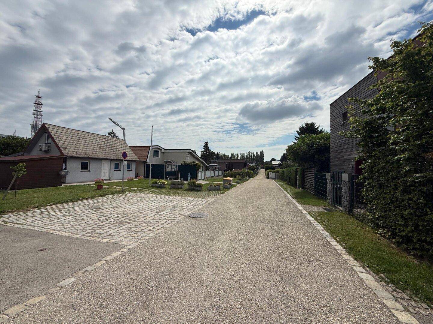 Blick auf die ruhige Wohnstraße mit gepflegten Häusern und Grünflächen in der Umgebung.