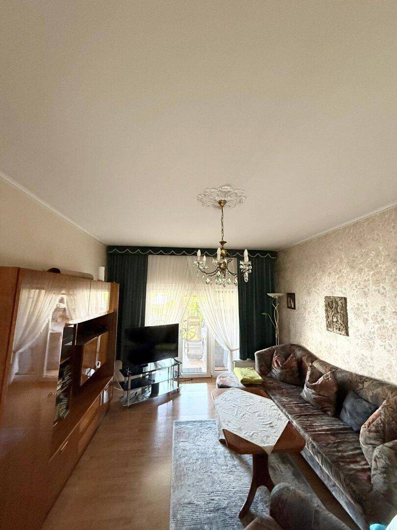 Gemütliches Wohnzimmer mit Sofa, Fernseher und Zugang zu einem Außenbereich.