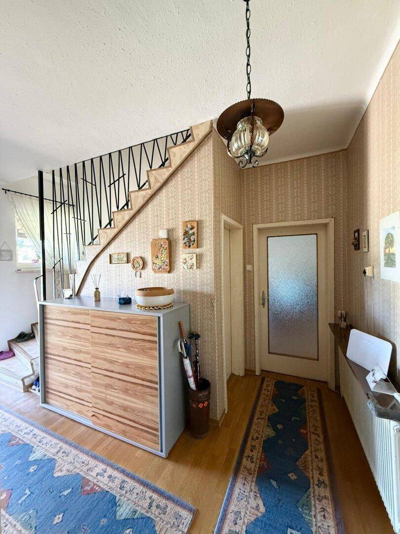 Eingangsbereich mit Treppe, modernem Sideboard und gemusterter Tapete.