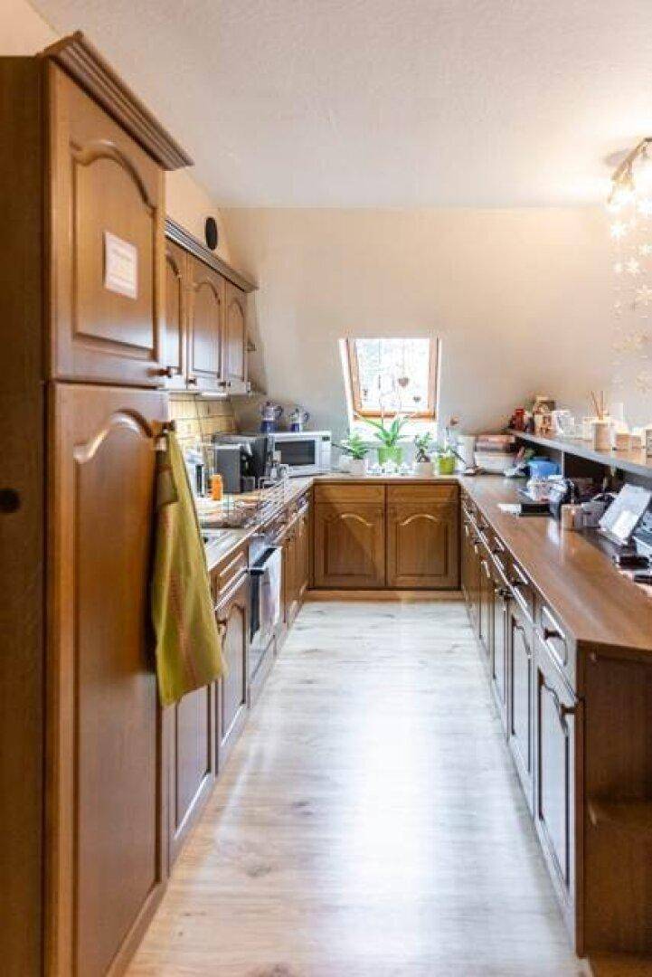 Schmale Küche mit Holzschränken und Dachfenster in der Dachgeschosswohnung.
